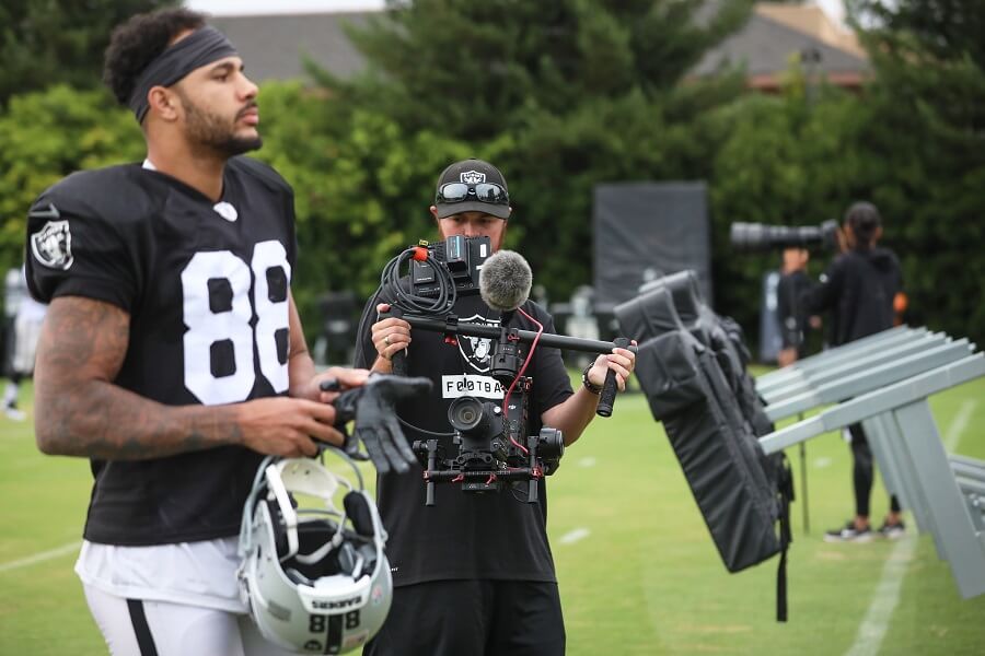 Film Connection grad Sam Freed in action, filming Raiders' WR Marcell Ateman in foreground. 
